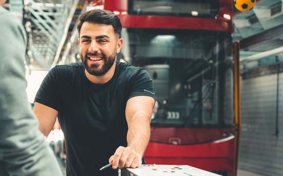 Werkstatt-Mitarbeitender lacht und steht vor Bus